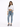A woman stands confidently in a cropped white long-sleeve top, light blue jeans, and gray fuzzy slippers.