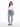A woman stands confidently in a cropped white long-sleeve top, light blue jeans, and gray fuzzy slippers.
