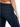 Close-up of a person wearing dark blue denim jeans, highlighting the back pocket and fitted silhouette.