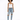 A model poses in a white tank top, distressed light blue jeans, and colorful sneakers against a plain background.
