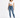 A woman stands confidently in a cropped white top and fitted blue jeans, paired with white sneakers.