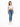 A woman stands in a fitted white crop top and blue skinny jeans, paired with white sneakers.