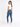 A woman with long hair wears a fitted white top and blue skinny jeans, paired with white sneakers.