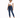 A model with curly hair wears a white cropped top and dark blue skinny jeans, paired with white sneakers.