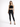 A model poses in a black lace crop top and fitted black jeans, paired with strappy black heels.