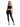 A model poses in a black lace crop top and fitted black jeans, paired with strappy high-heeled sandals.