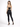 A woman stands with her back to the camera, wearing a black cropped top and fitted black jeans, paired with high-heel...