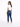 A woman with long hair wears a white t-shirt and blue skinny jeans, standing in a relaxed pose.