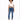 A model poses in a cropped white top with a drawstring and blue skinny jeans, paired with white sneakers.