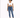 A model poses in a cropped white top and fitted blue jeans, paired with white sneakers against a plain background.