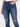 Close-up of a person wearing dark blue ripped jeans with a high waist and a hand in the pocket.