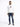 A man stands confidently in a white hoodie with a graphic design, paired with distressed blue jeans and black sneakers.