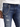 Close-up of distressed blue jeans featuring a silver chain attached to the belt loop, styled with a white long-sleeve...