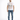 A man stands confidently in a white graphic t-shirt and distressed blue jeans, paired with white sneakers.