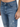 Close-up of blue denim jeans featuring a distressed design and a fitted silhouette, highlighting the front pockets an...