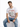 A man sits casually wearing a white graphic t-shirt with a lion design and distressed blue jeans.