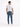 A man stands with his back to the camera, wearing a white t-shirt and blue jeans, paired with white sneakers.