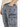 Close-up of distressed gray jeans with side pockets, worn with a light-colored shirt.