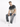 A man sits on a white cube wearing faded gray jeans and a gradient t-shirt, paired with white sneakers.