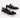 Black canvas sneakers with white laces and rubber soles, featuring a casual design and contrasting stitching.