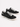 Black canvas sneakers with white laces and rubber soles, featuring a casual design and contrasting stitching.
