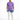 A man stands wearing a purple t-shirt and light blue jeans with a tie-dye pattern, paired with white sneakers.