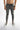 Slim-fit gray jeans with distressed knee details, paired with stylish black and white sneakers.