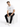 A man sits on a white cube, wearing a casual white t-shirt and black jeans, paired with white sneakers.