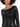 A close-up of a woman wearing a fitted black sequin dress with long sleeves and a boat neckline.