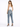 A woman stands with her back to the camera, wearing light blue jeans and a white tank top, paired with black heels.