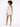 A model showcases a fitted, one-shoulder dress with a shimmering finish, paired with strappy heels.