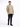A man wearing a light beige t-shirt and black jeans stands confidently against a plain background.