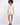 A model poses in a light beige button-up top and matching shorts, complemented by black open-toe heels.