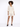 A model poses in a light beige button-up shirt and matching shorts, complemented by black heeled sandals.