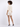 A model with curly hair wears a light-colored, short-sleeve top and matching shorts, paired with black heels.