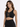 A model poses in a black cropped top with a lace-up front and gold eyelets, paired with a matching skirt.