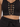 Black cropped top featuring a lace-up front with gold eyelets, paired with high-waisted black trousers.