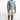 A man stands confidently in a light blue short-sleeve shirt and distressed white shorts, paired with casual sneakers.