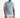 A man stands confidently in a light blue short-sleeve shirt paired with distressed white shorts.