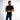 A man poses in a fitted black t-shirt with a bold graphic design, paired with blue jeans.