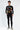 A model wearing a black long-sleeve shirt featuring colorful graphic designs and text, paired with black skinny jeans.