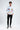 A young man stands confidently in a white long-sleeve shirt adorned with colorful graphics and text, paired with blac...