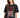 A woman in a black oversized tee featuring a graphic design with flames, a heart, and bold text.