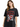 A woman in a black oversized tee featuring a graphic design with flames, a heart, and bold text.
