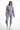 A model poses in a light purple cropped hoodie and matching jogger pants, paired with white sneakers.