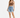 A woman stands confidently in a fitted brown crop top and distressed denim shorts, paired with white sneakers.