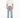 A man stands wearing a loose-fitting beige t-shirt and embellished light blue jeans with a relaxed fit.