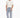 A man stands wearing a light beige oversized t-shirt and light blue jeans adorned with decorative studs.