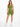 A model poses in olive green fitted shorts and a matching one-shoulder crop top, paired with white sneakers.