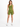 A model poses in a fitted olive green outfit featuring a one-shoulder top and matching shorts.
